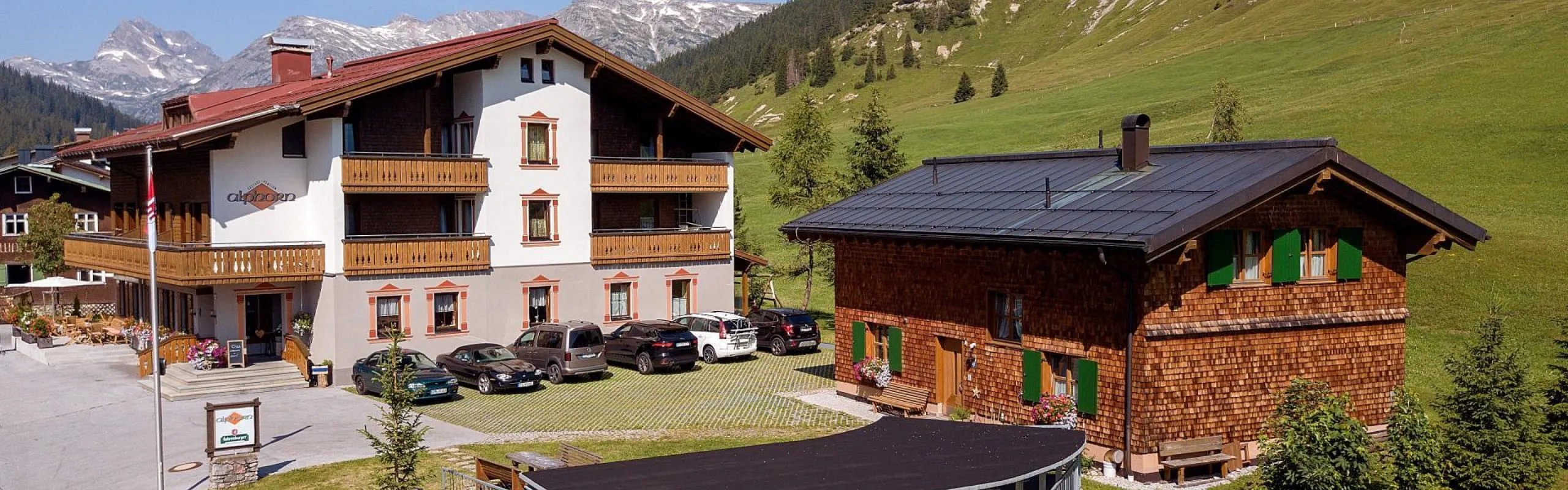 Alpine house with two buildings and parking in picturesque landscape