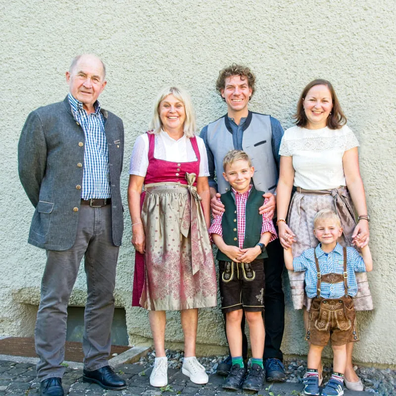Family picture with five people in traditional attire against a light gray background