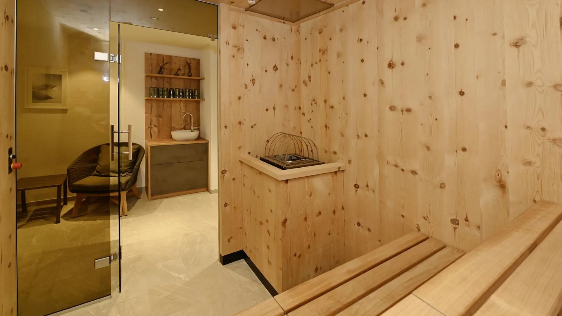 Wood-paneled sauna with a bench and glass door