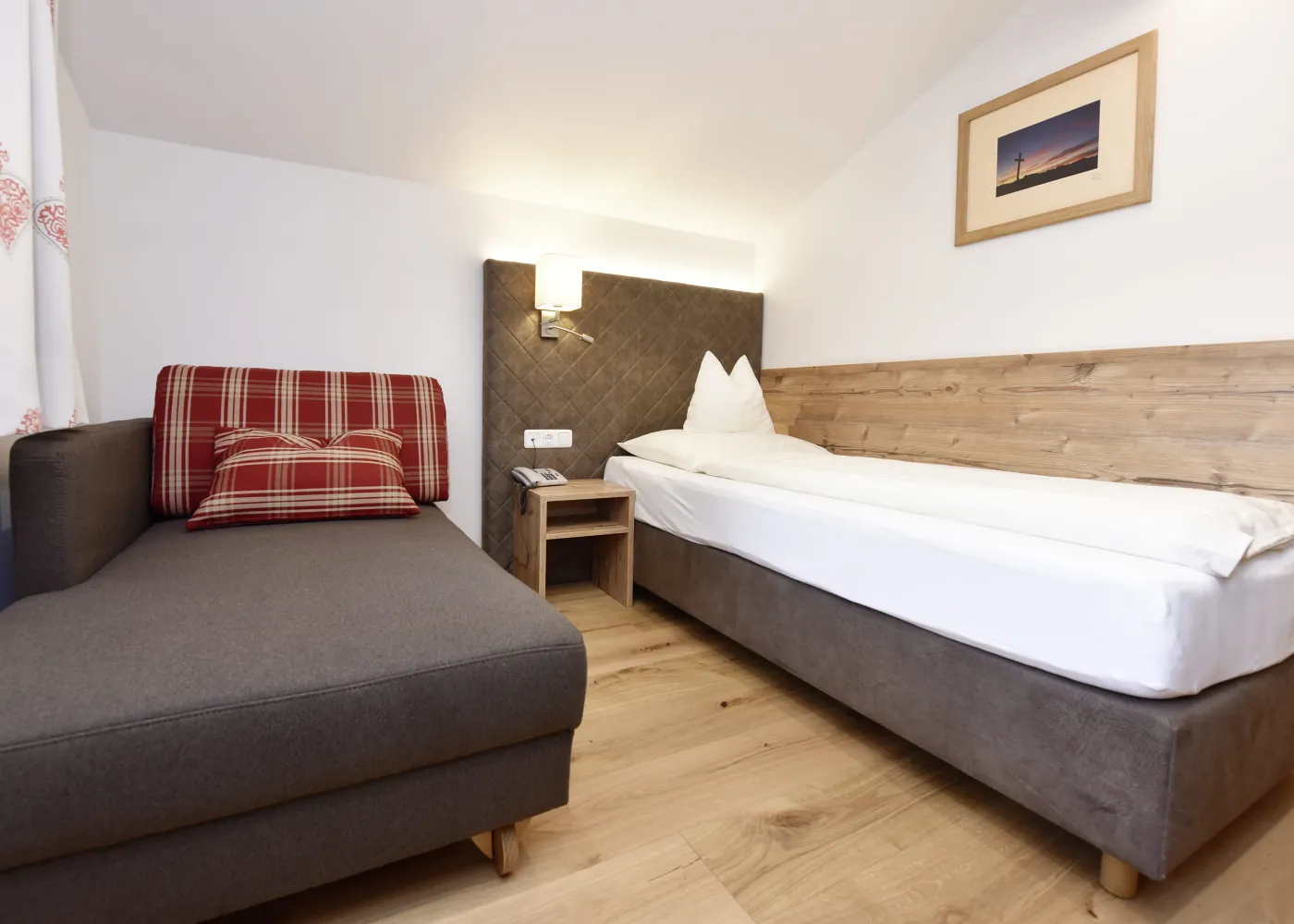 Innenansicht eines Zimmers mit einem gepolsterten Sofa und einem Bett.