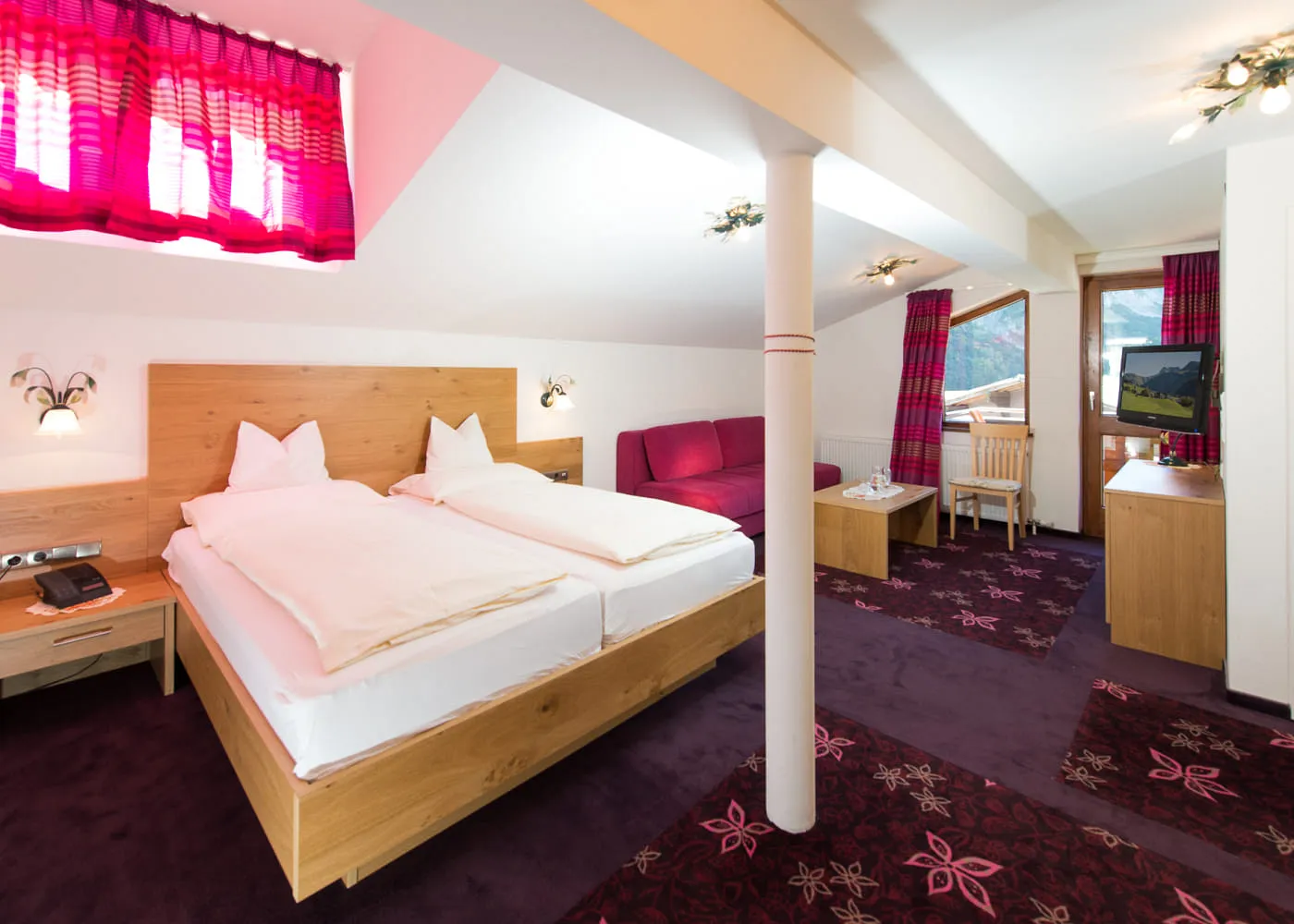 Helles Hotelzimmer mit zwei Betten und rot gestreiften Vorhängen.