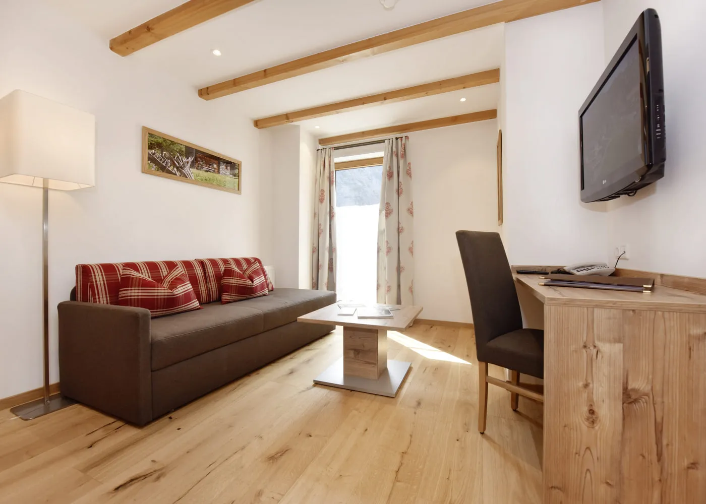 Heller Wohnraum mit Sofa, Tisch, Stuhl und Fernseher an der Wand