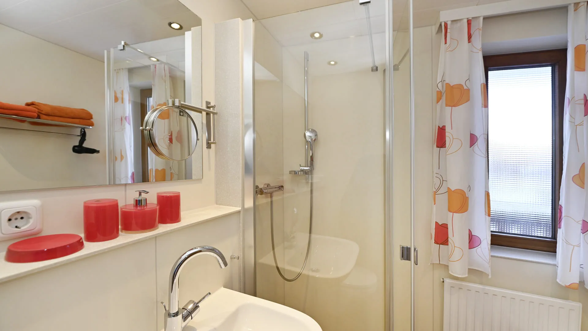 Modernes Badezimmer mit Dusche, Waschbecken und bunten Handtüchern