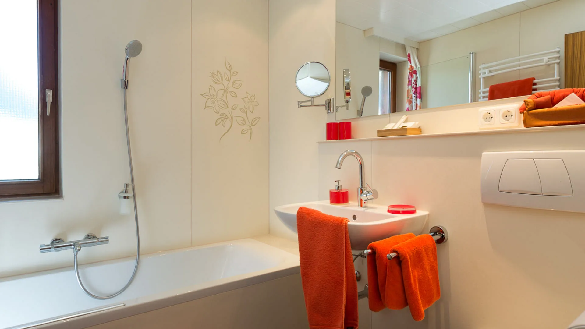 modernes Badezimmer mit Dusche, Badewanne und orangen Handtüchern