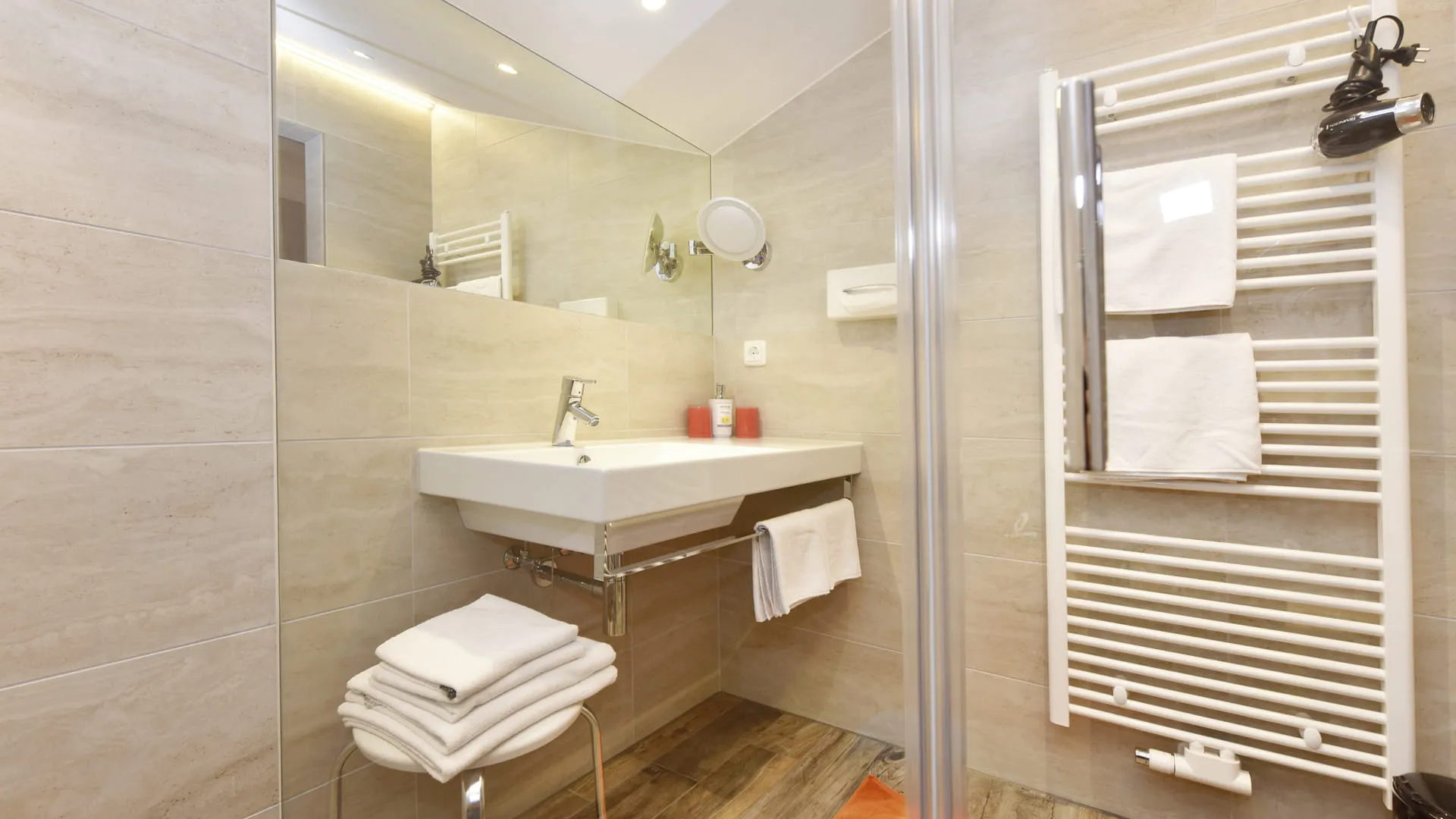 Modernes Badezimmer mit Waschbecken, Handtüchern und Handtuchheizkörper.