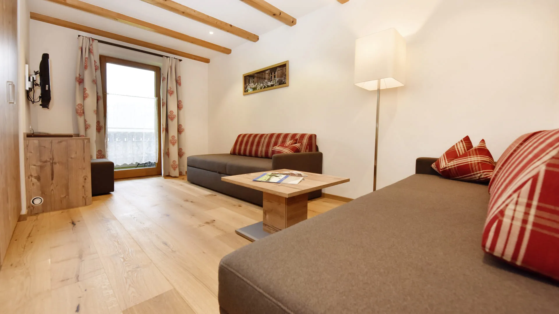 Heller Wohnraum mit Holzfußboden, Sofa, Tisch und Fensteraussicht.