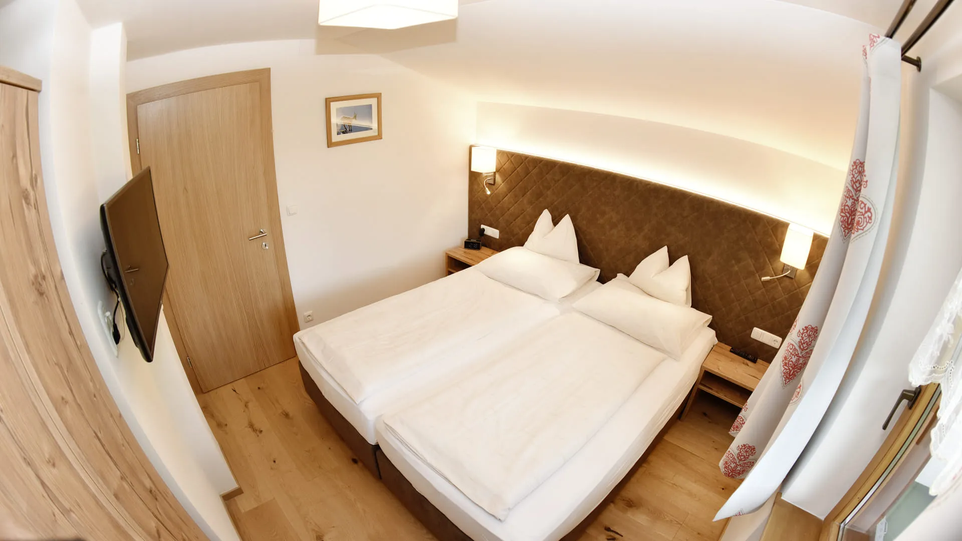 Zimmer mit zwei Betten, Holzinterieur und Fernseher an der Wand