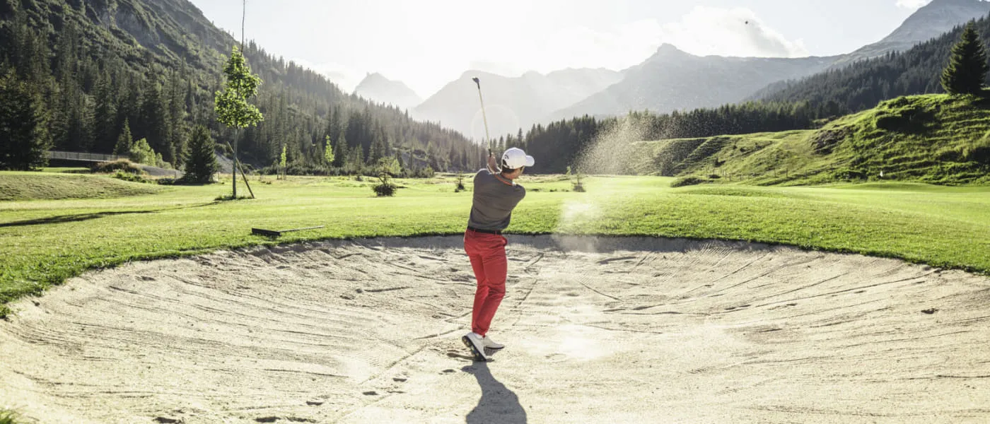 Golfer im Sandbunker in Lech Zürs, Berge im Hintergrund