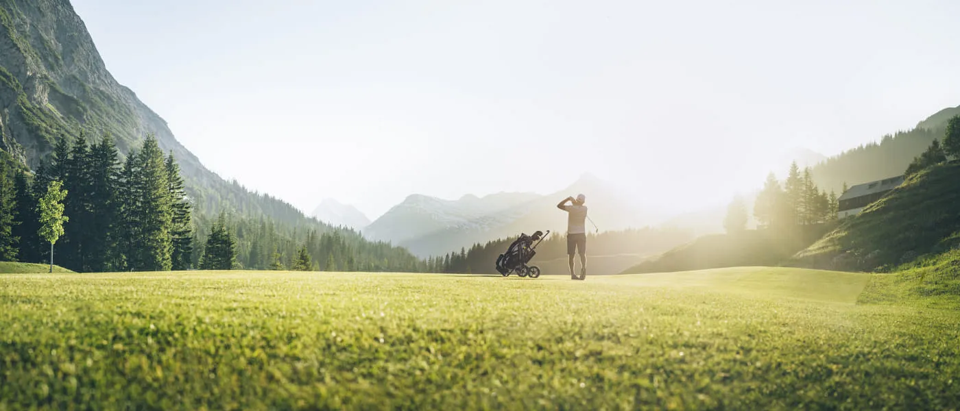 Golfplatz in Lech Zürs mit einem Golfer und Gebirgen im Hintergrund