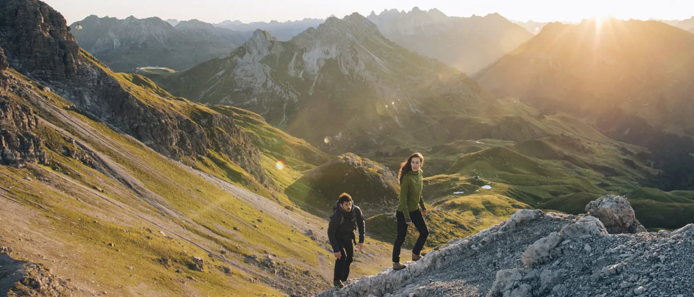 Zwei Wanderer in den Alpen bei Lech Zürs, umgeben von Bergen und Sonnenlicht