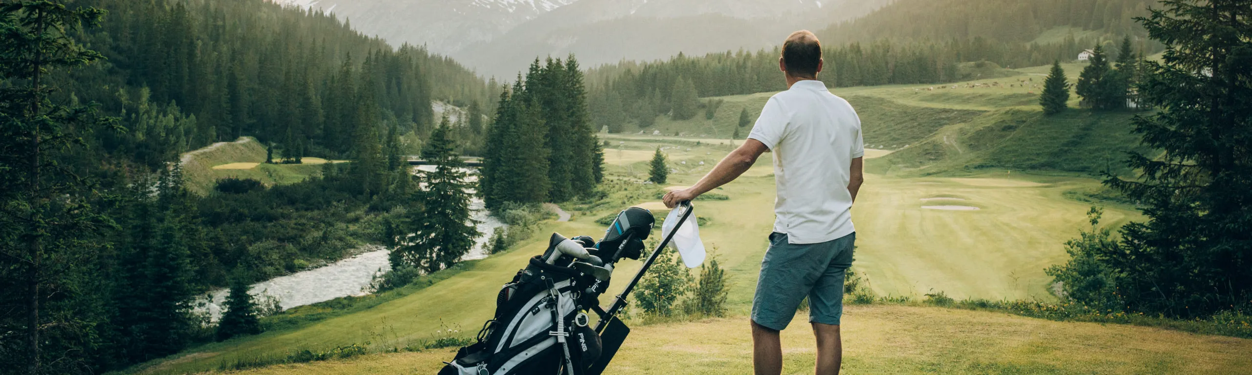 Golfer mit einer Tasche auf einem üppigen Golfplatz in Lech Zürs
