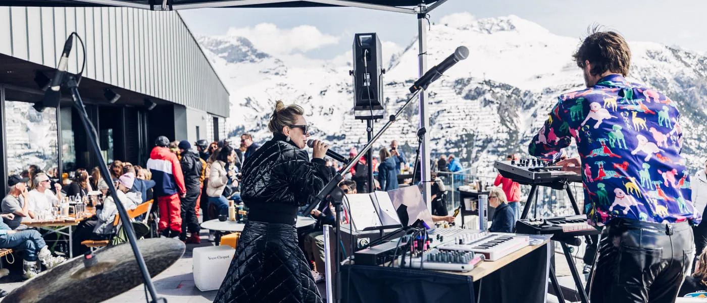 Musikaufführung auf dem Tanzcafe Arlberg Festival mit Zuschauern und schneebedeckten Bergen im Hintergrund