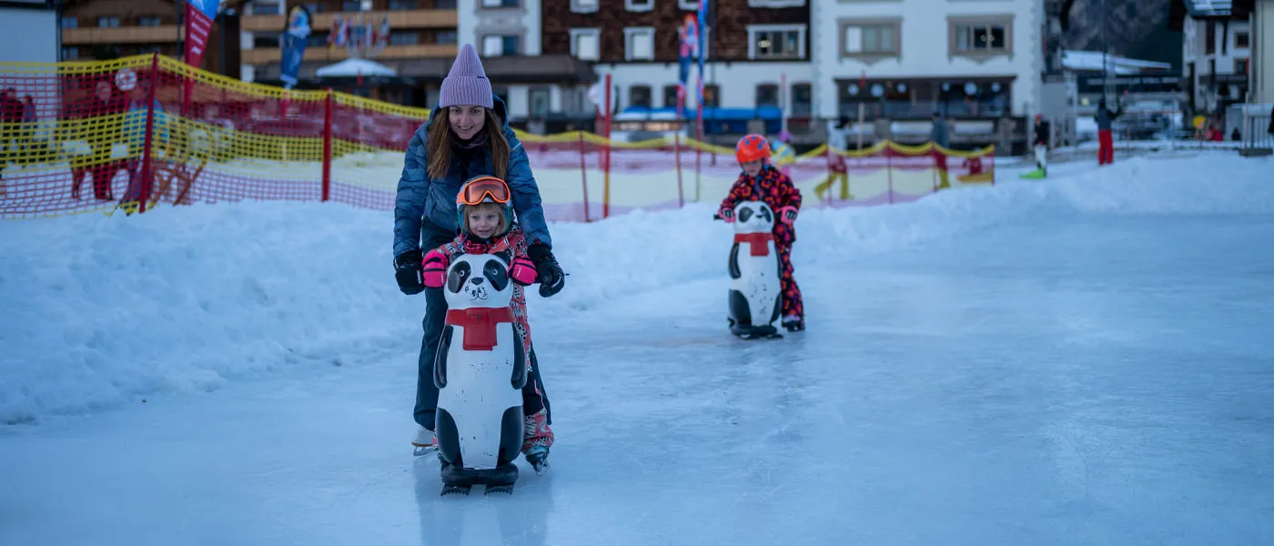 Eislaufplatz in Zürs, Kinder mit Pinguin-Eisgleitern auf dem Eis