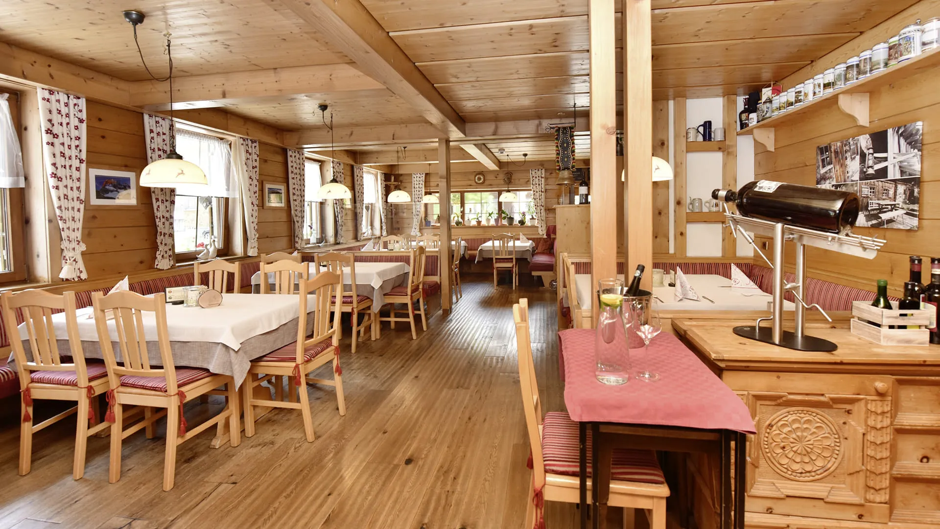 Gemütliches Restaurant mit Holztischen und Stühlen, warmem Licht.