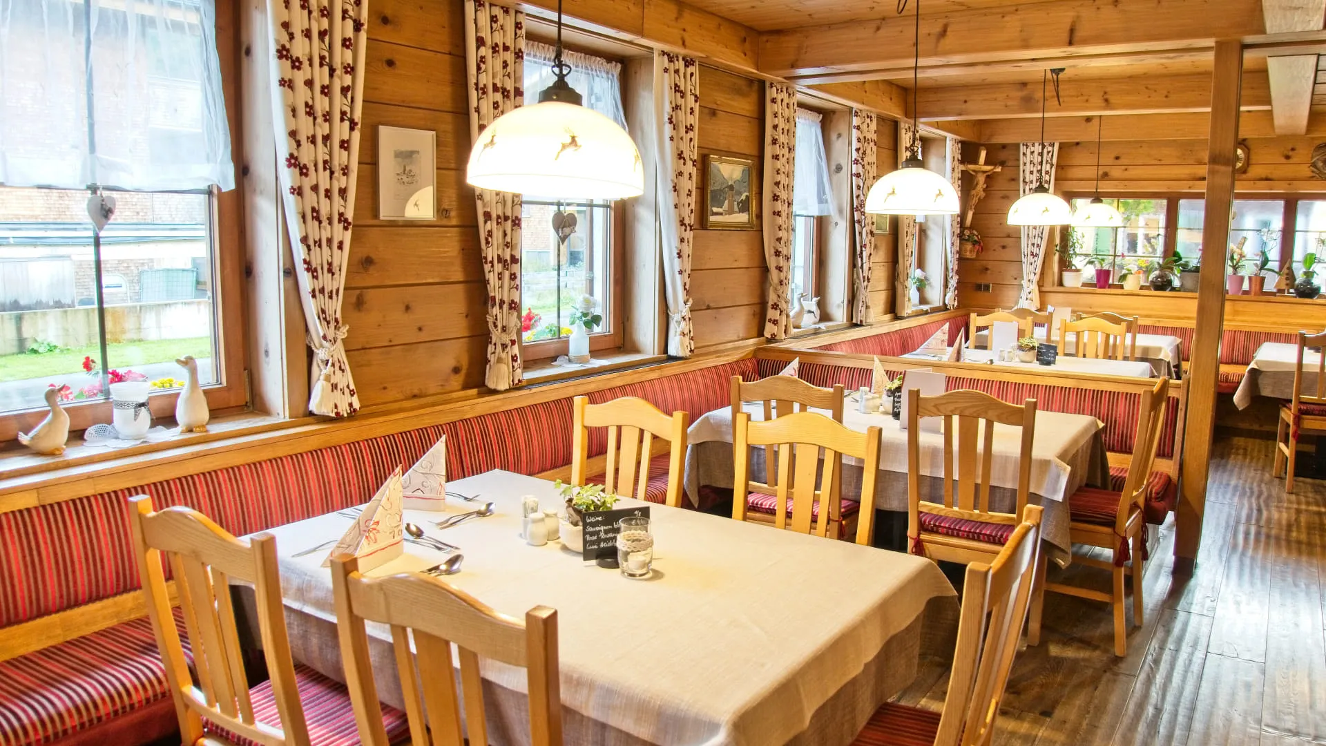Gemütliches Restaurant mit Holzmöbeln und rot gestreiften Sitzbänken.