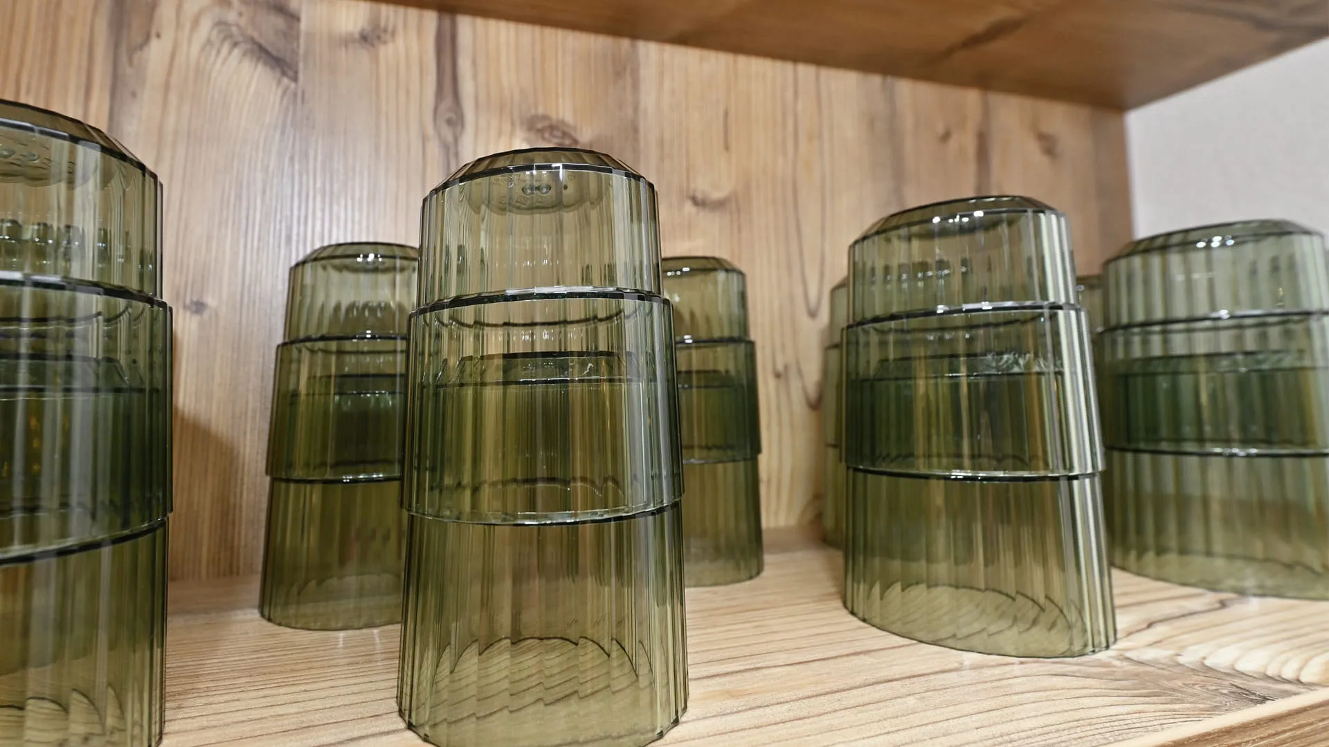 gestapelte grüne Glasbecher auf einem Holzregal
